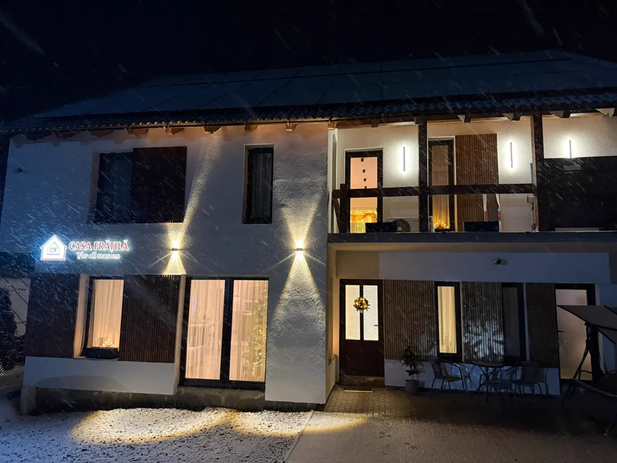 Casa Frătilă at night in snowfall — main facade illuminated